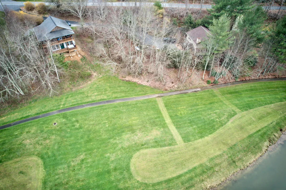 A wide view of the house, manicured lawn, and bordering tree line under open sky. A gently curving path leads guests across the lawn, suggesting easy access to outdoor walks and space to stretch out. The tranquil, natural environment is front and center in the image, offering an ideal setting for guests exploring the outdoors with their pets.